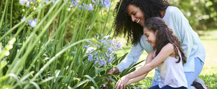 a woman and her daughter planting flowers in a garden